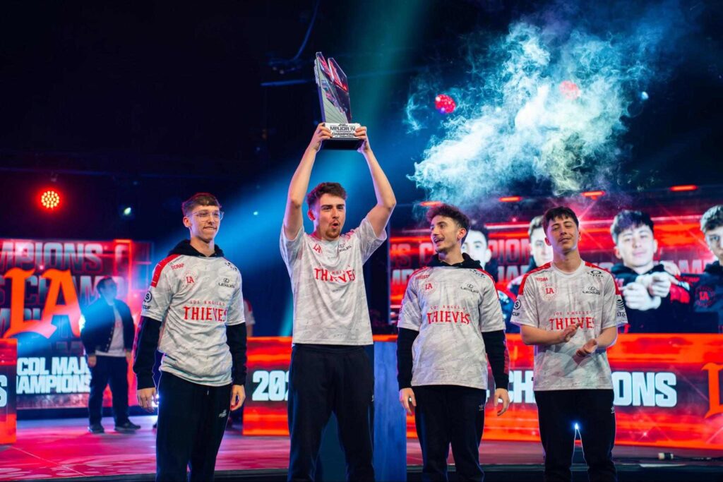 teams-competing-at-cdl-2026-major-3-1024x683-1 Los Angeles Thieves players celebrating on stage after a Call of Duty League victory, holding the championship trophy, representing one of the twelve franchise teams competing at CDL 2026 Major 3.